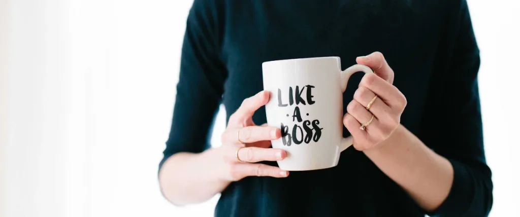 Woman holding coffee mug that reads 'like a boss'